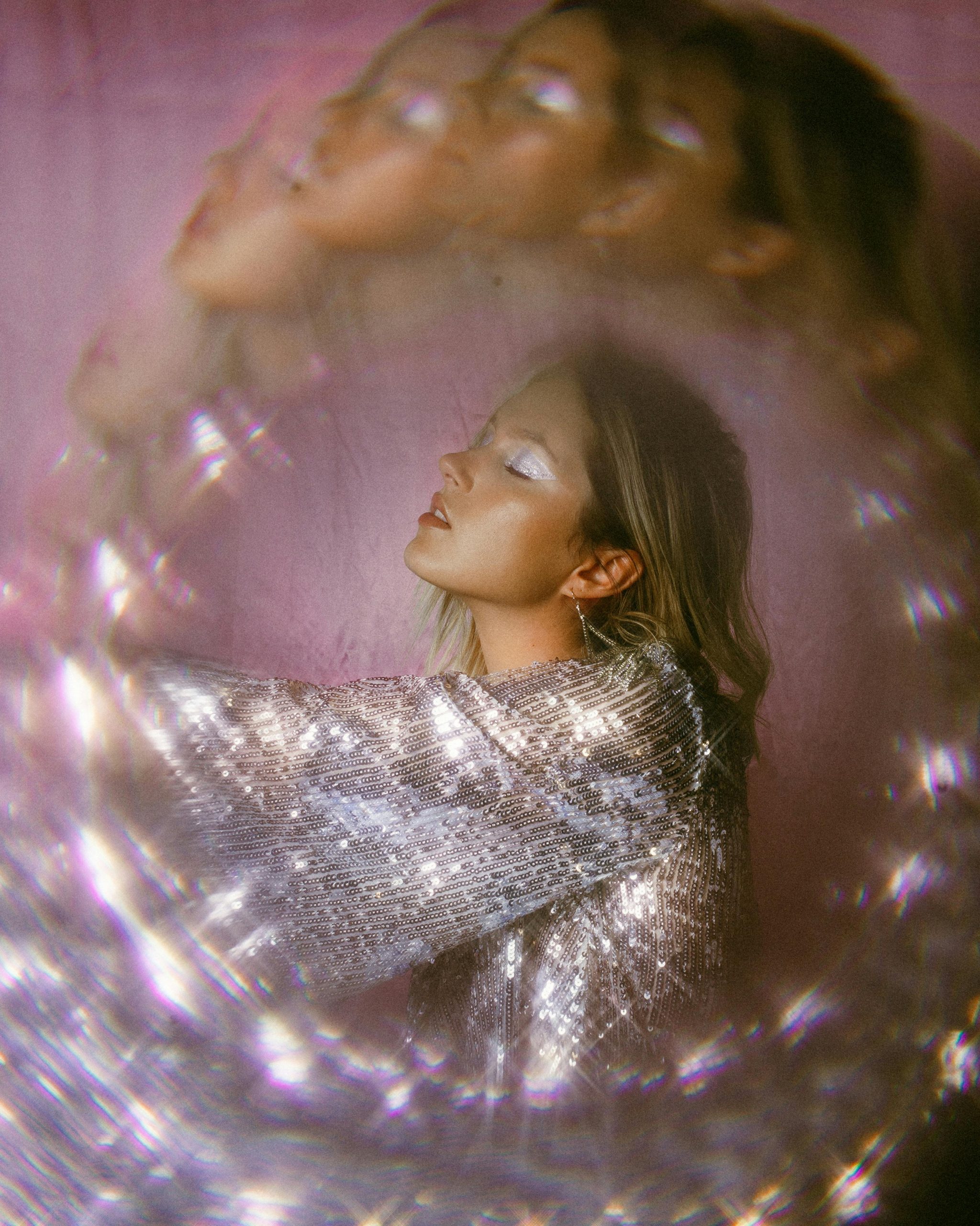 Artistic portrait of a woman with shimmering silver attire and double exposure effect.